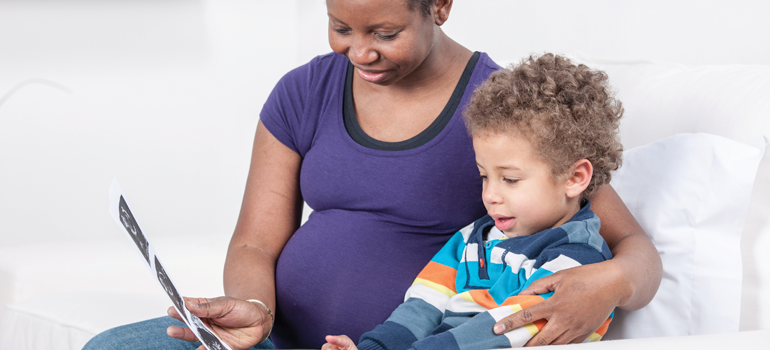 Pregnant mother showing young son ultrasound photo