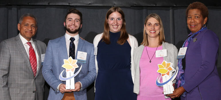 Group of 3 women and 2 men standing with awards