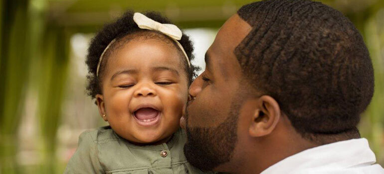 Dad kissing baby daughter on the cheek
