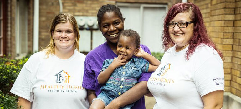 Mothe and baby with Healthy Homes staff members