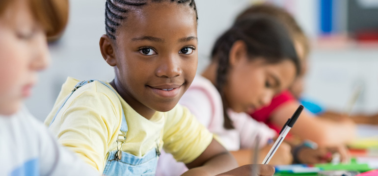 a child smiling with other kids sitting next to her