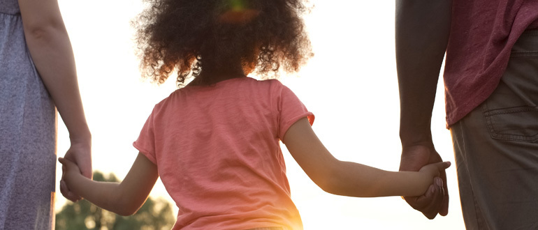 Child holding two adults hands