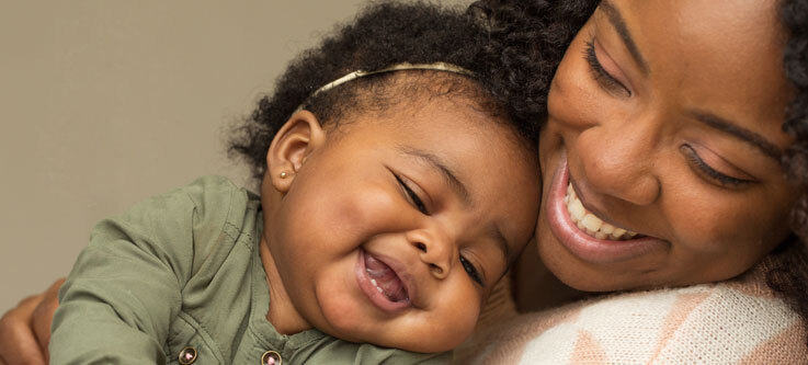 Mother holding baby laughing together