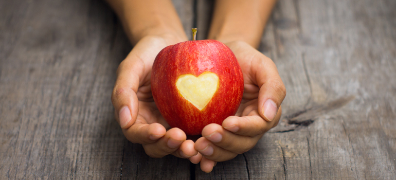 Hands holding apple with heart