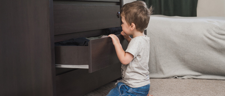 Child looking in a half-open bedroom drawer