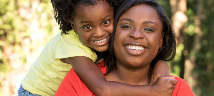 Mother with young daughter hugging her neck