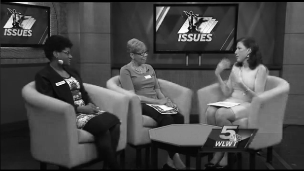 Three women on a television news set seated talking