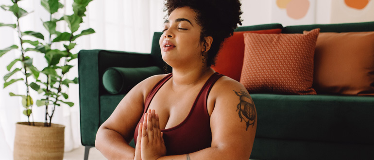 Woman sitting with hands clasped and eyes closed