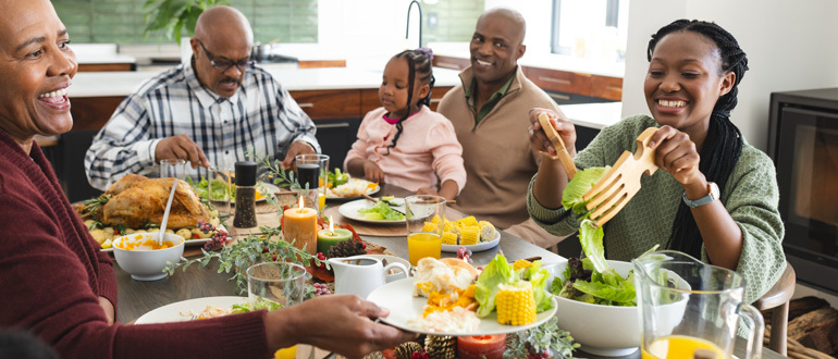 a family smiling and eating dinner together around a table